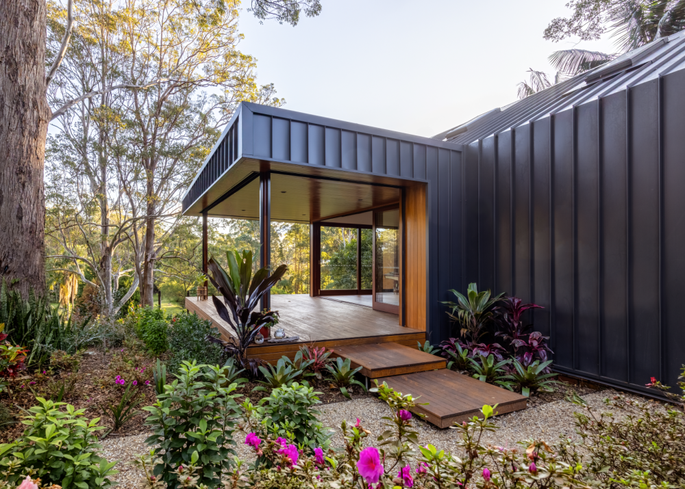 Contemporary home featuring LYSAGHT® ZENITH® range ENSEAM® cladding in a sleek dark finish, complemented by warm timber decking and large glass doors.