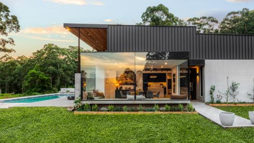 Expansive home featuring COLORBOND® Monument® roofing, blending seamlessly with natural surroundings and outdoor living spaces.
