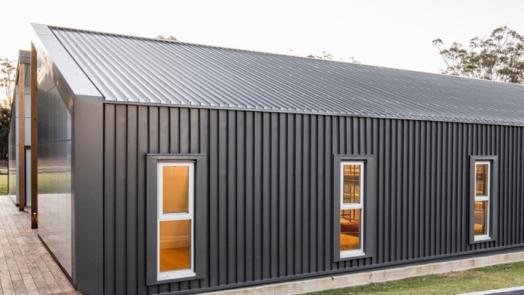 Modern building with Woodland Grey® COLORBOND® steel cladding, vertical panels, and warm-lit windows.