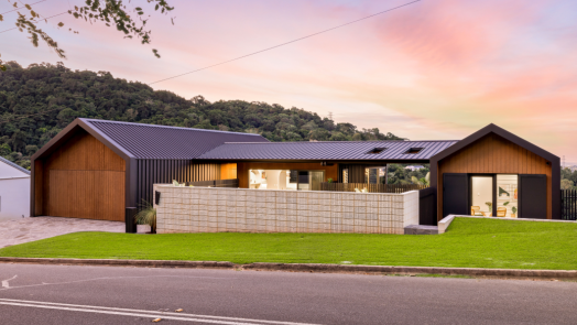 Modern house exterior featuring LYSAGHT® ZENITH® range ENSEAM® cladding in a sleek, dark finish, combined with warm timber paneling and natural stone elements.