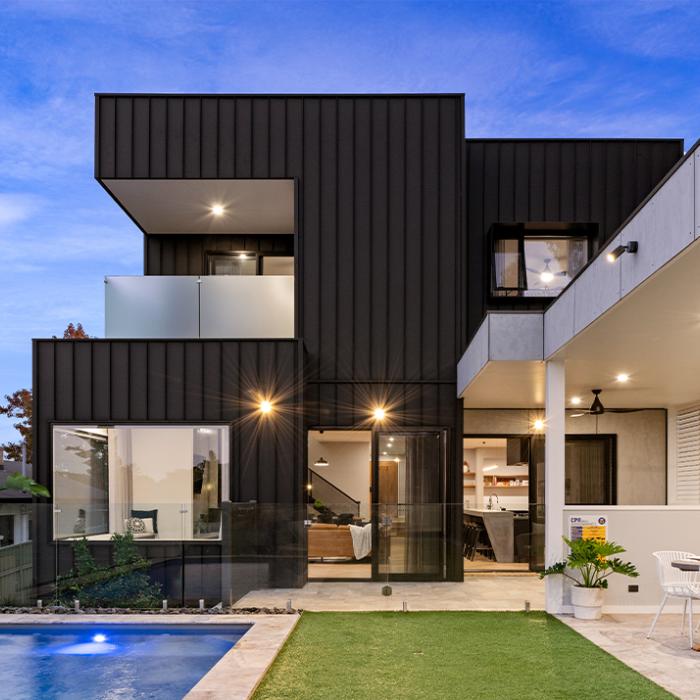 Stylish two-story house with COLORBOND® Monument® steel cladding, showcasing large windows and an outdoor living space